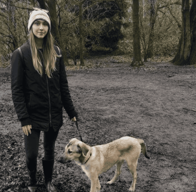 A photo of Paws2Rescue team member Karolina stood outside in a muddy area alongside a beautiful dog